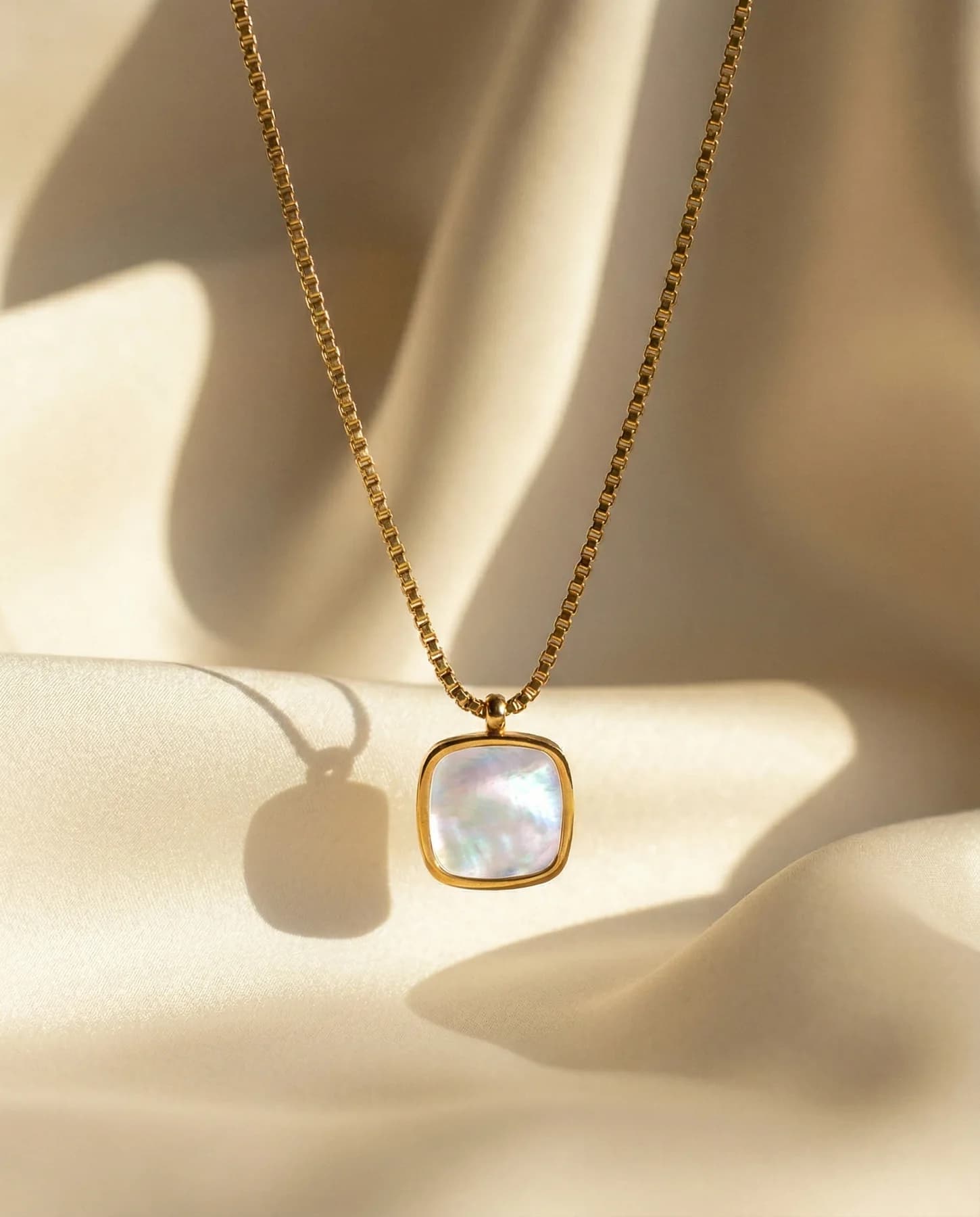 Gold pendant photographed on softly lit ivory fabric for B Classy